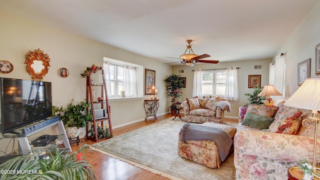 living room with visible vents, wood finished floors, a wealth of natural light, and baseboards