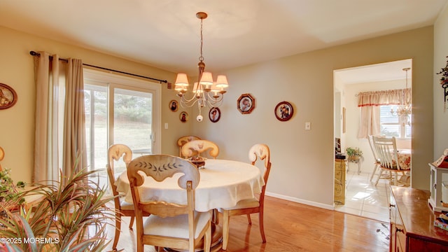 dining area with baseboards, light wood-type flooring, and an inviting chandelier