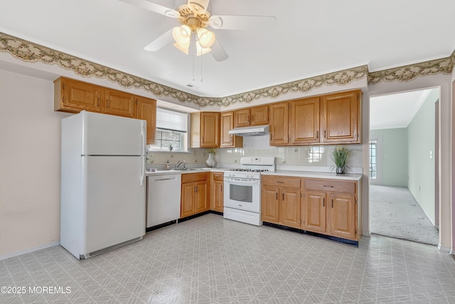 kitchen featuring light floors, light countertops, a sink, white appliances, and under cabinet range hood