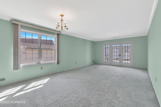 spare room with a notable chandelier, visible vents, french doors, ornamental molding, and carpet