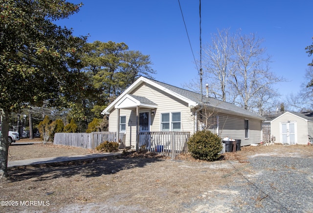 bungalow with fence, an outdoor structure, and a storage unit