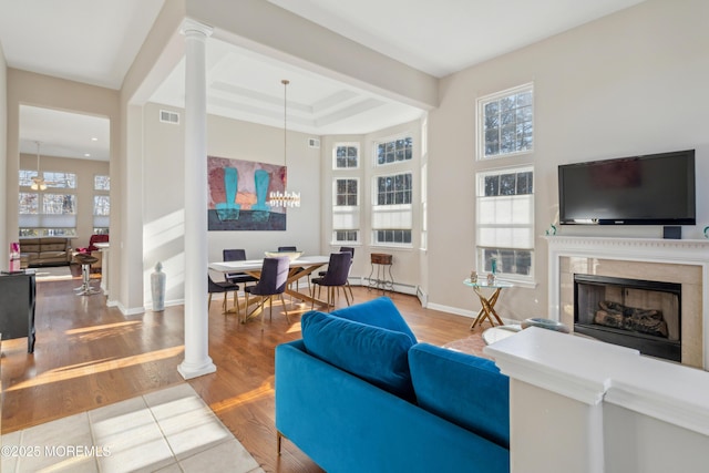 living room featuring decorative columns, visible vents, wood finished floors, and a high end fireplace