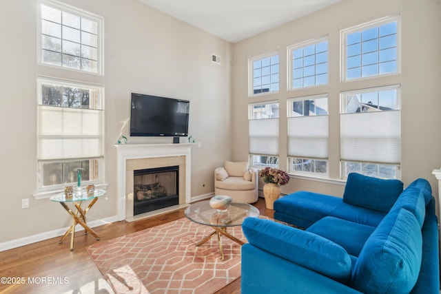 living room with a wealth of natural light, visible vents, baseboards, and wood finished floors