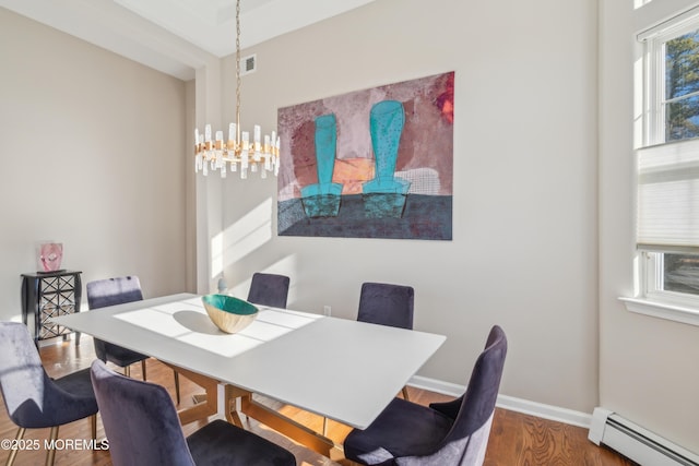 dining space with baseboards, visible vents, wood finished floors, baseboard heating, and a notable chandelier