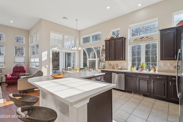 kitchen featuring dishwasher, light countertops, dark brown cabinets, and visible vents