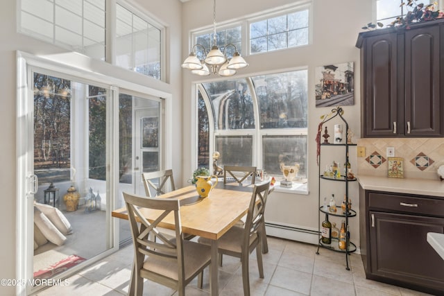 dining area with a chandelier, light tile patterned floors, a baseboard radiator, and a towering ceiling