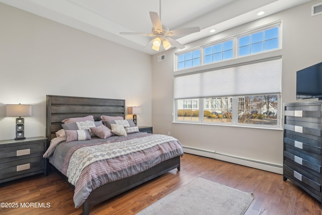 bedroom with a baseboard radiator, wood finished floors, and visible vents