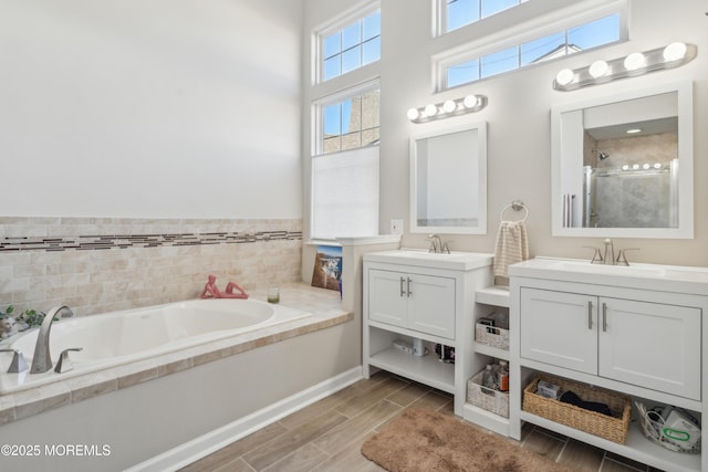 full bathroom with wood finish floors, a garden tub, two vanities, a sink, and a shower stall