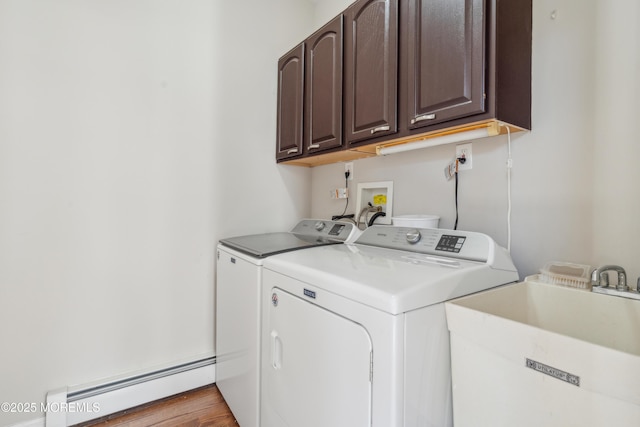 laundry area with a sink, baseboard heating, washing machine and dryer, and cabinet space