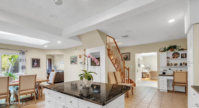 kitchen featuring light tile patterned floors, visible vents, a center island, white cabinetry, and open shelves