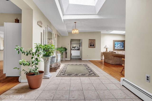 foyer entrance featuring a skylight, light tile patterned floors, baseboards, and a baseboard radiator