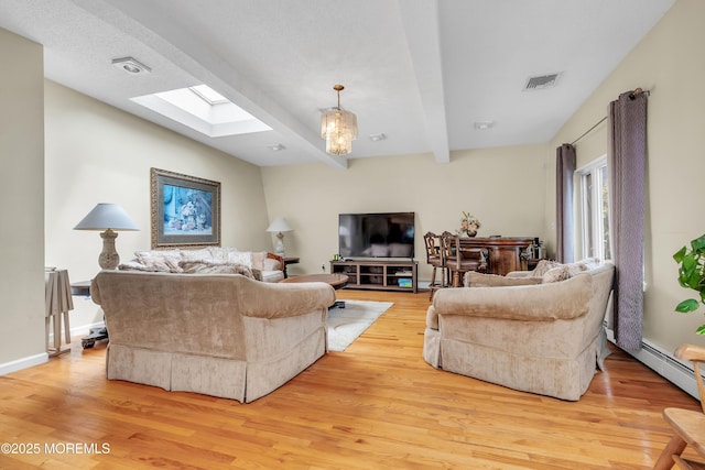 living area with a skylight, visible vents, baseboards, light wood-style flooring, and beam ceiling