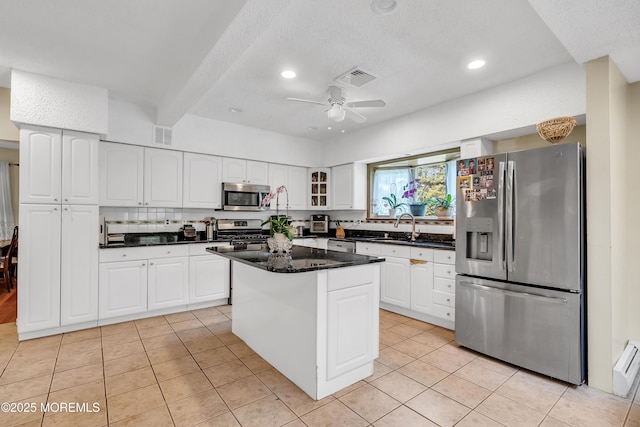 kitchen with visible vents, glass insert cabinets, appliances with stainless steel finishes, a center island, and white cabinetry