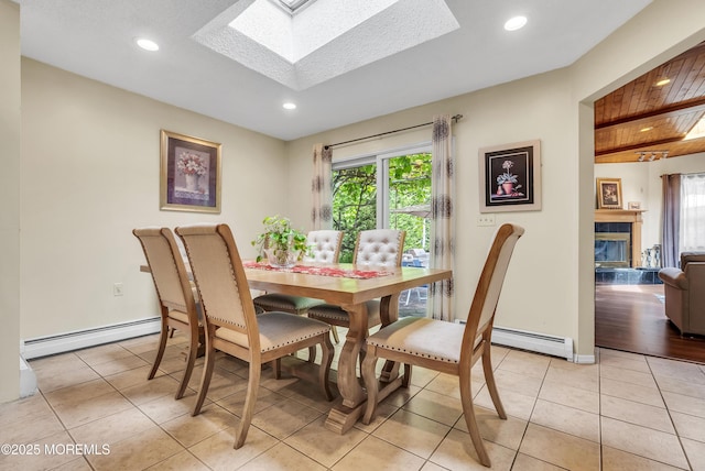 dining room with a baseboard heating unit, a skylight, a glass covered fireplace, and light tile patterned floors