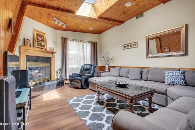 living area with visible vents, wood finished floors, a tile fireplace, wooden ceiling, and beamed ceiling