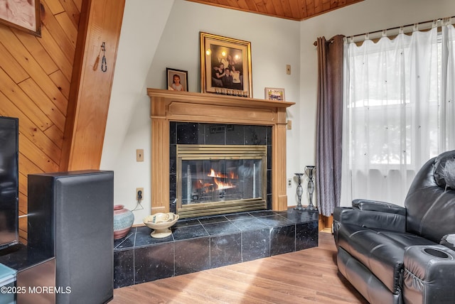 living room with wood ceiling, wood finished floors, and a tile fireplace