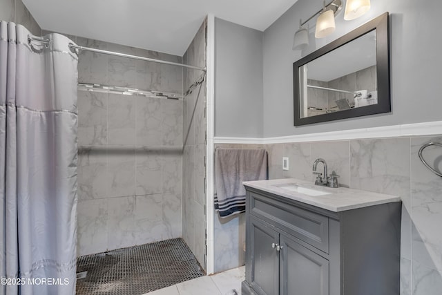 bathroom with wainscoting, a shower stall, tile walls, and vanity