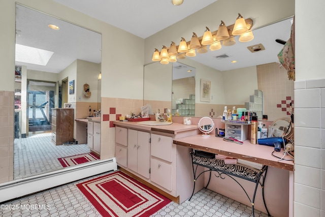 bathroom with a skylight, tile walls, wainscoting, a baseboard radiator, and a sink