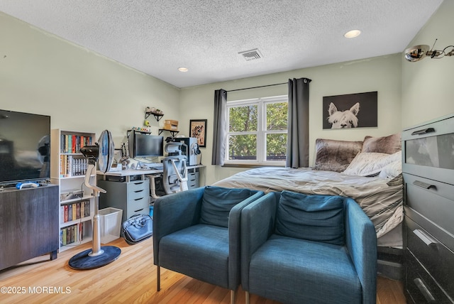 bedroom featuring light wood-type flooring, visible vents, and a textured ceiling