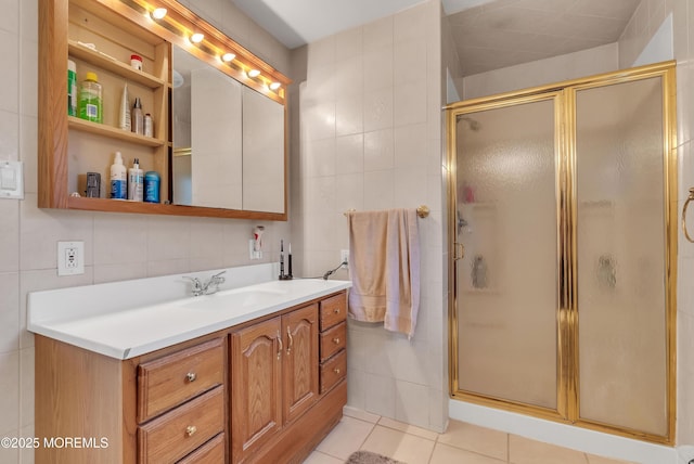 full bath with a stall shower, tile patterned flooring, tile walls, and vanity