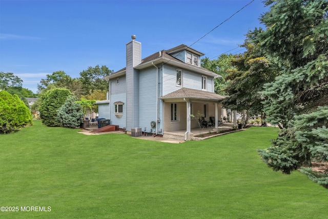 rear view of property featuring central AC, a chimney, a lawn, and a patio