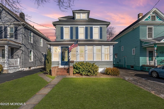 american foursquare style home featuring roof with shingles and a front yard