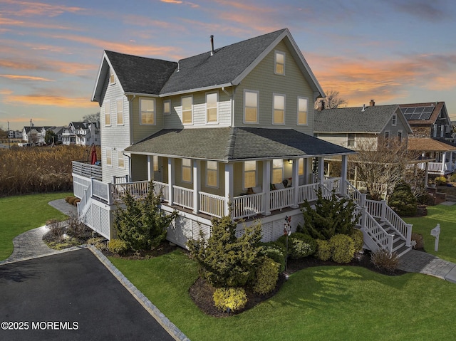 view of front of property with driveway, a shingled roof, a porch, and a front yard