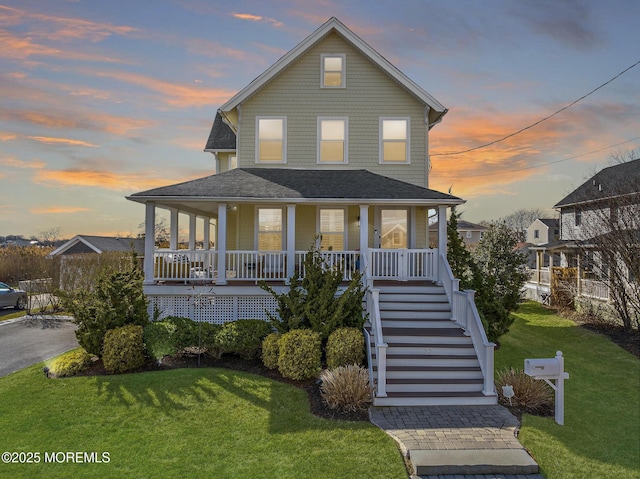 view of front facade with stairs, a porch, a front lawn, and a shingled roof