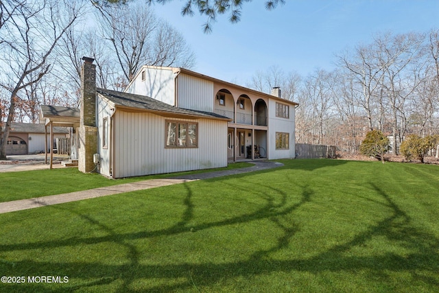 view of front of house with a front lawn, fence, a chimney, and a balcony