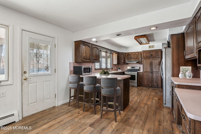 kitchen with stainless steel appliances, baseboard heating, light countertops, and dark wood-style flooring