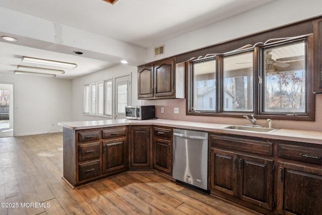 kitchen featuring stainless steel appliances, light countertops, visible vents, a sink, and dark brown cabinets