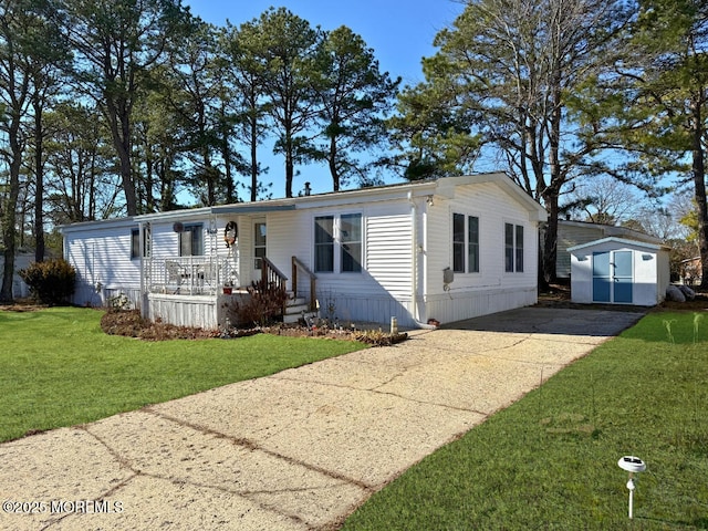 manufactured / mobile home with a storage shed, a front yard, concrete driveway, and an outdoor structure