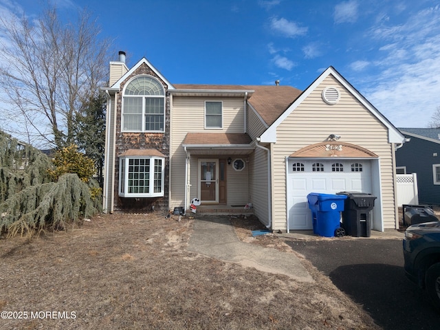 traditional-style home with a garage, entry steps, driveway, and a chimney