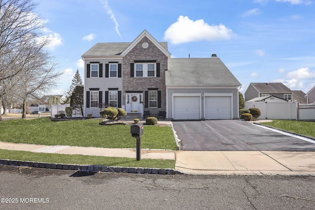 view of front of home featuring a garage, aphalt driveway, fence, a front lawn, and brick siding