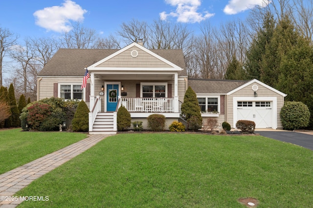 view of front of home featuring a garage, aphalt driveway, roof with shingles, covered porch, and a front yard