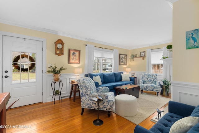 living area with light wood-type flooring, crown molding, and wainscoting