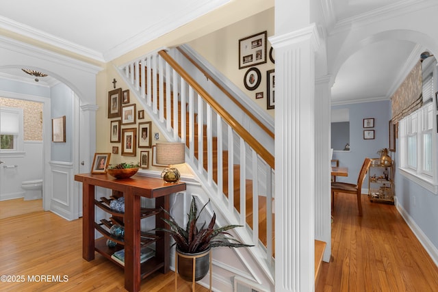 staircase with arched walkways, visible vents, wood finished floors, and decorative columns