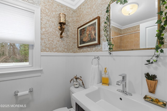 bathroom featuring a shower, crown molding, toilet, wainscoting, and wallpapered walls