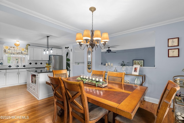 dining space with light wood-style floors, ornamental molding, baseboards, and ceiling fan with notable chandelier