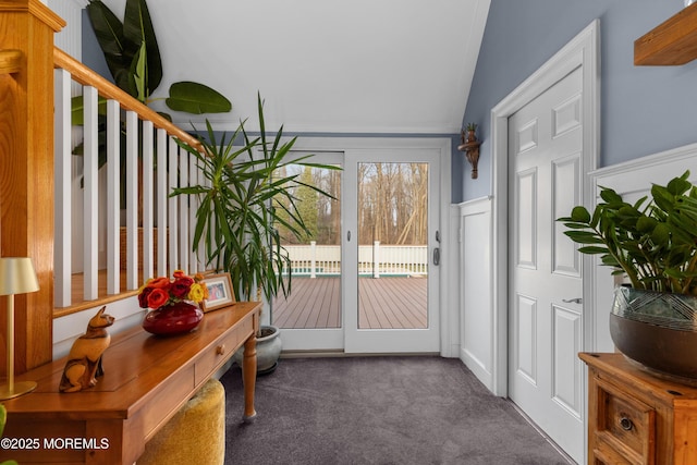 doorway featuring dark colored carpet and vaulted ceiling