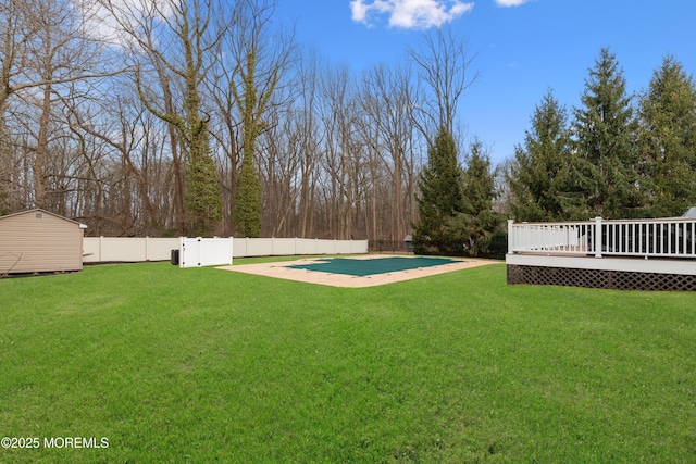 view of yard featuring a fenced in pool, an outbuilding, a shed, a fenced backyard, and a wooden deck