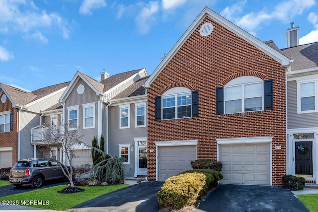 townhome / multi-family property featuring driveway, a garage, and brick siding