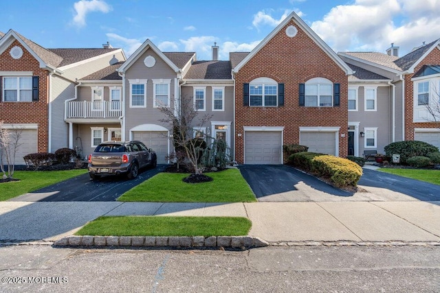 view of property featuring a garage, driveway, brick siding, and a front yard