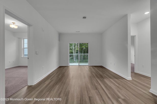 spare room with baseboards and wood finished floors