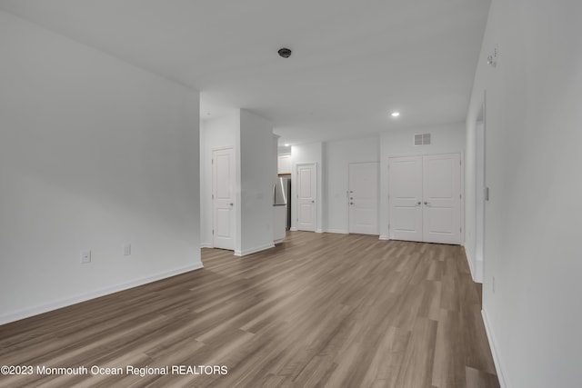 spare room featuring light wood-type flooring, visible vents, and baseboards