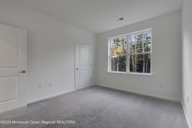 empty room featuring baseboards, visible vents, and carpet flooring