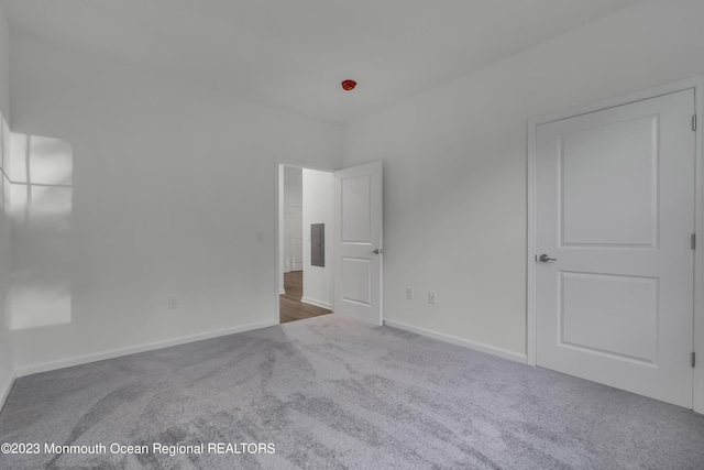 unfurnished bedroom featuring carpet, electric panel, and baseboards