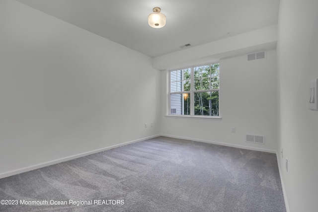 carpeted spare room with visible vents and baseboards