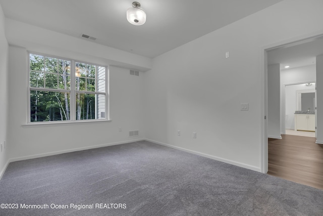 empty room with dark colored carpet and visible vents