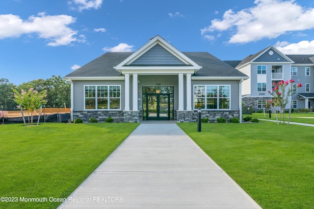 exterior space featuring stone siding, french doors, roof with shingles, and a front yard